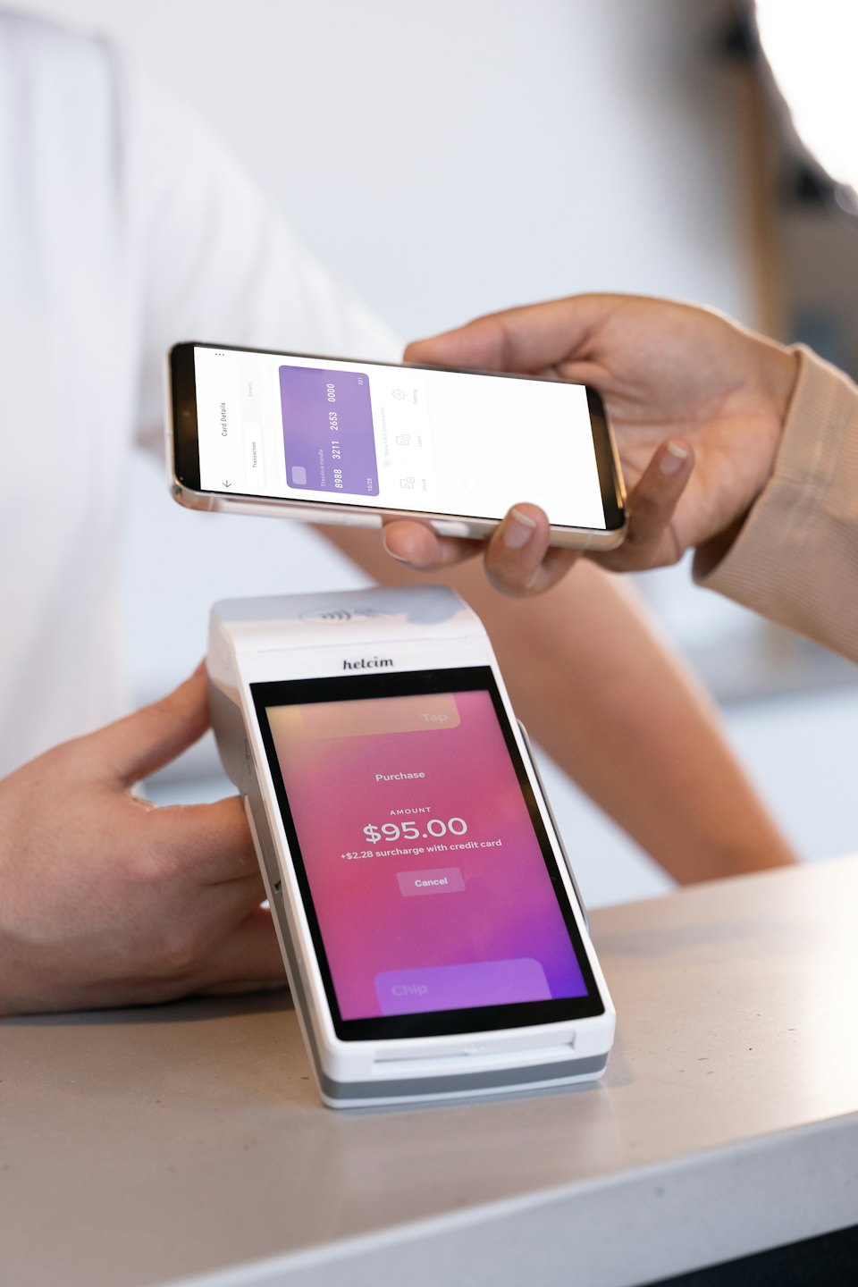 Person paying with phone over payment terminal.